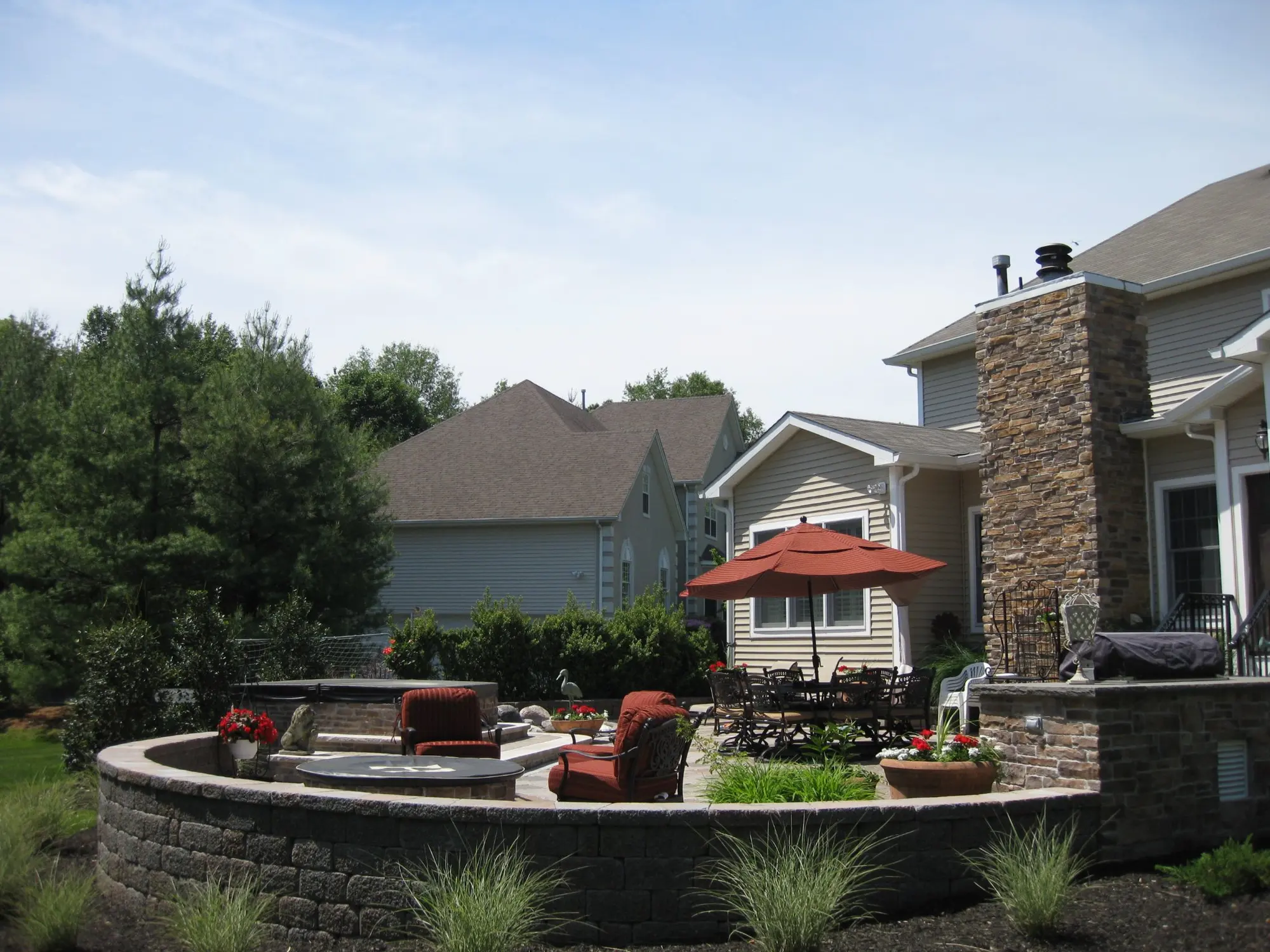 Curved stone terrace with fire pit and grill pavilion