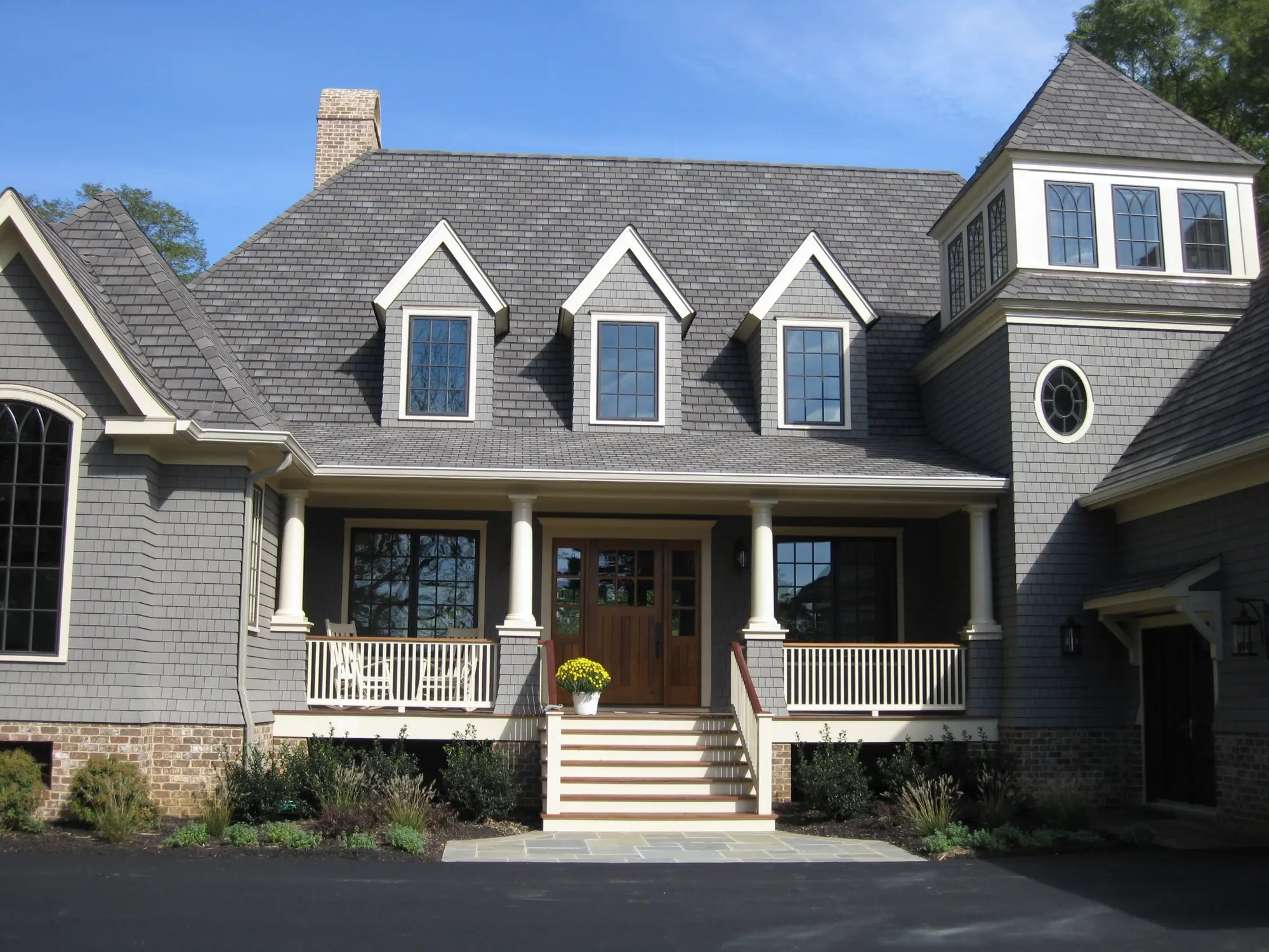 Grey stone estate home with columns and brick base