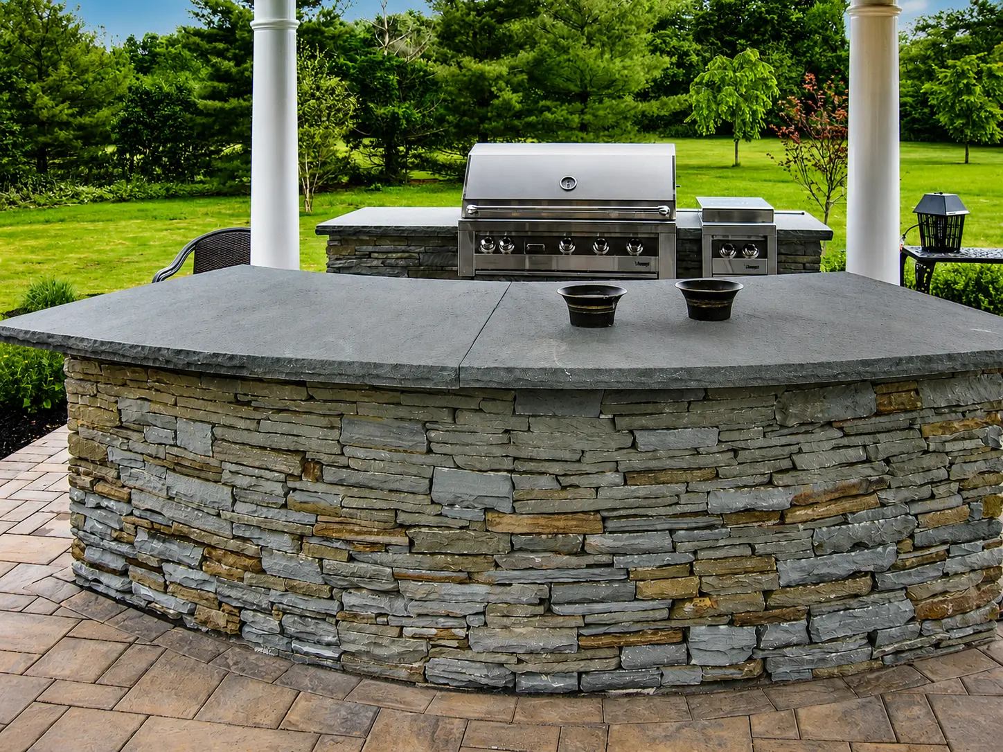 Custom outdoor kitchen under pergola with built-in grill, countertops and seating